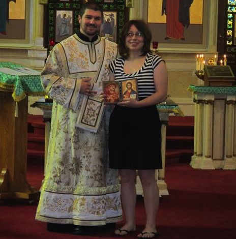 Photo of Gabriel Bilas presenting an icon to college graduate Alexandra Rebuck