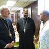 Photo of Archbishop Mark and Father John speaking to a visitor during the parish picnic