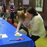 Photo of mom helping her young daughter grab some cake