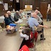 Photo of parishoners sitting at a brown table and facing the right side of the picture. They are watching the drawing of raffle tickets that is taking place off-camera.