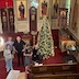 Photo taken from the choir loft shows five peopl standing to the left of the decorated Christmas tree.