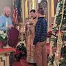 Father Fravel is standing in front of the iconostas, holding the chalis and ready to give communion. A man stands on either side of him to to assist with communion. The man on the left is wearing a light blue shirt and is holding a deep red cloth that will be held below each communicant as they recieve communion so that any drips may be caught by the cloth.