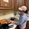 A woman in the hall kitchen is removing paska breads from their round baking pans.