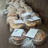 Paska breads in plastic bags are sitting on a table against a wall and are ready to be distributed.