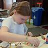 A young girl working intently on her craft project.