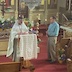 Photo Fr. Barnabas reading from the lecturn on Holy Saturday while a man holding a large candle stands to his left.