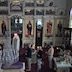 Photo of candlebearers on Holy Saturday, waiting near the back side of the Epitaphios (tomb icon), which is surrounded by flowers, as Fr. Barnabas emerges from behind the altar. He is holding a candelabra made up of four candles.