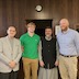 Fr. Barnabas poses with three male parishoners in the church hall.