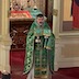 Wearing green vestments, Father Barnabas Fravel stands in front of the Royal Doors and presents the Holy Gifts to the congregation.