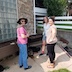 Three woman standing at a waist-high planter turn towards the camera and smile.