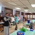 Fr. Barnabas says a prayer at the start of the picnic. Two tables with food and picnic supplies are in view along with a few parishioners.