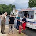 Several people stand in line at Pepe's ice cream truck, which appears in the right side of the frame. There's also a fire hydrant on the sidewalk nearby.