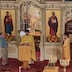 View from the choir loft of Father Aleksey standing at a lecturn in front of the Royal Doors, facing and reading to the congregation.