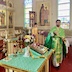 Imagery similar to that in the previous photo, but this picture was taken from the left-front corner of the table, and Fr. Aleksy is now walking towards the table and looking at the camera. The altar boy is now visible in the center of the photo.