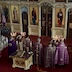Five priests in purple vestments are standing in a semi-circle facing the iconostasis. They are standing between the center icon table and the two steps leading up to the walkway that runs the length of the iconostasis.