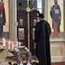 Photo Fr. Aleksey standing in front of, and facing, the Royal Doors. He is wearing a black vestment and has his head bowed slightly in prayer.