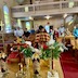 View from the front of the church looking towards the congregation. The center table appears in the foreground, with Fr. Aleksey bowing his head as he stands in front of it, on the far side of the table. Parishioners are seen standing in the pews behind him.