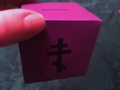 A purple alms box with an Orthodox cross on it